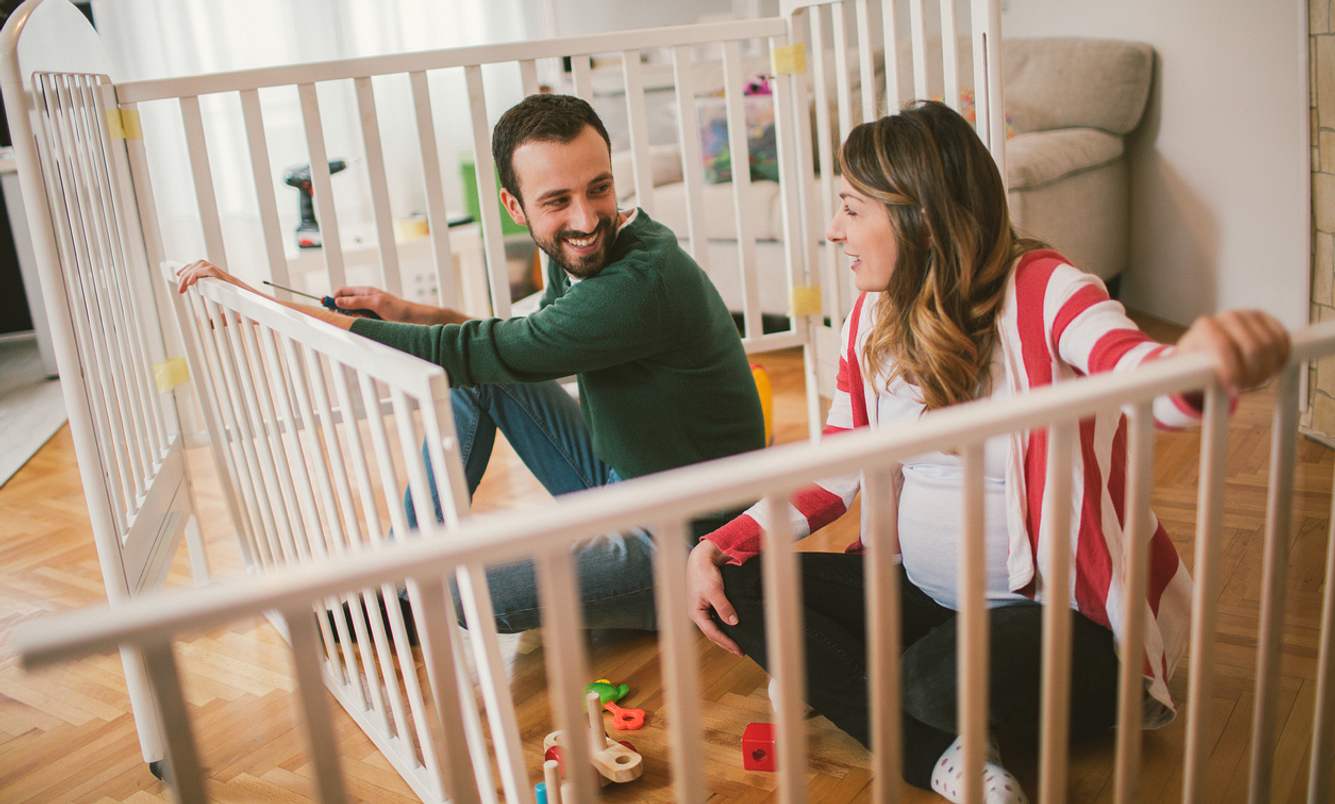 Schwangere Frau und Mann bauen ein Kinderbett auf