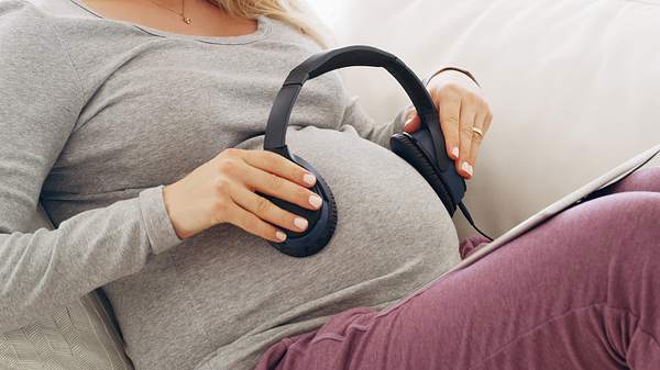 Schwangere Frau mit Kopfhörern auf dem Bauch - Foto: iStock/Yuri_Arcurs