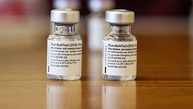 Zwei Fläschchen mit dem Impfstoff von Biontech/Pfizer im Vordergrund auf einem Tisch - Foto: IMAGO / ZUMA Wire