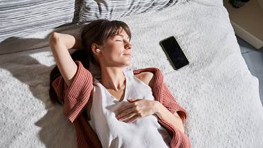 Frau liegt im Bett - Foto: iStock/YakobchukOlena