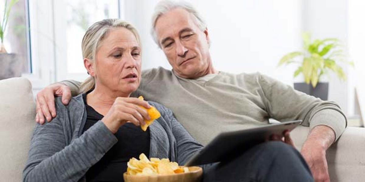 Paar isst Chips auf Couch - Gift für die Leber