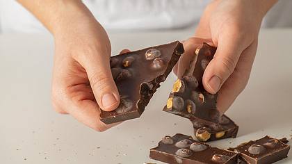 Person zerbricht eine Tafel Nussschokolade - Foto: iStock/ solidcolours