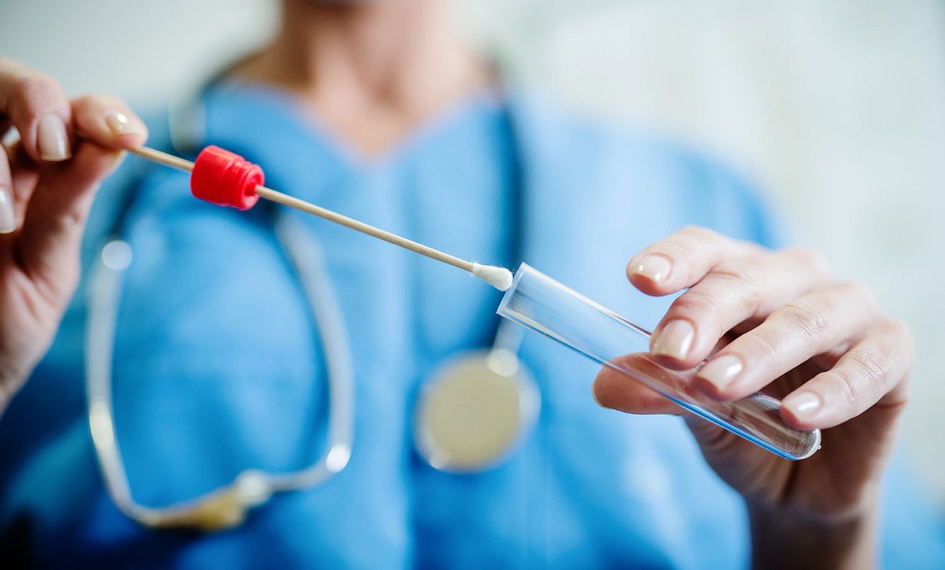 Eine Ärztin steckt ein Wattestäbchen mit einerm Abstrich in eine Plastikhülle