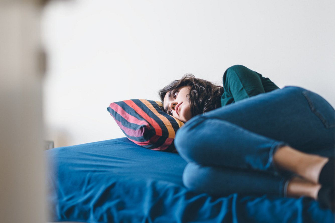 adhs-depression Junge Frau mit ADHS und Depression liegt traurig auf einem Bett