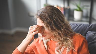 Eine Frau sitzt mit schlechter Laune auf dem Sofa - Foto: iStock/elenaleonova