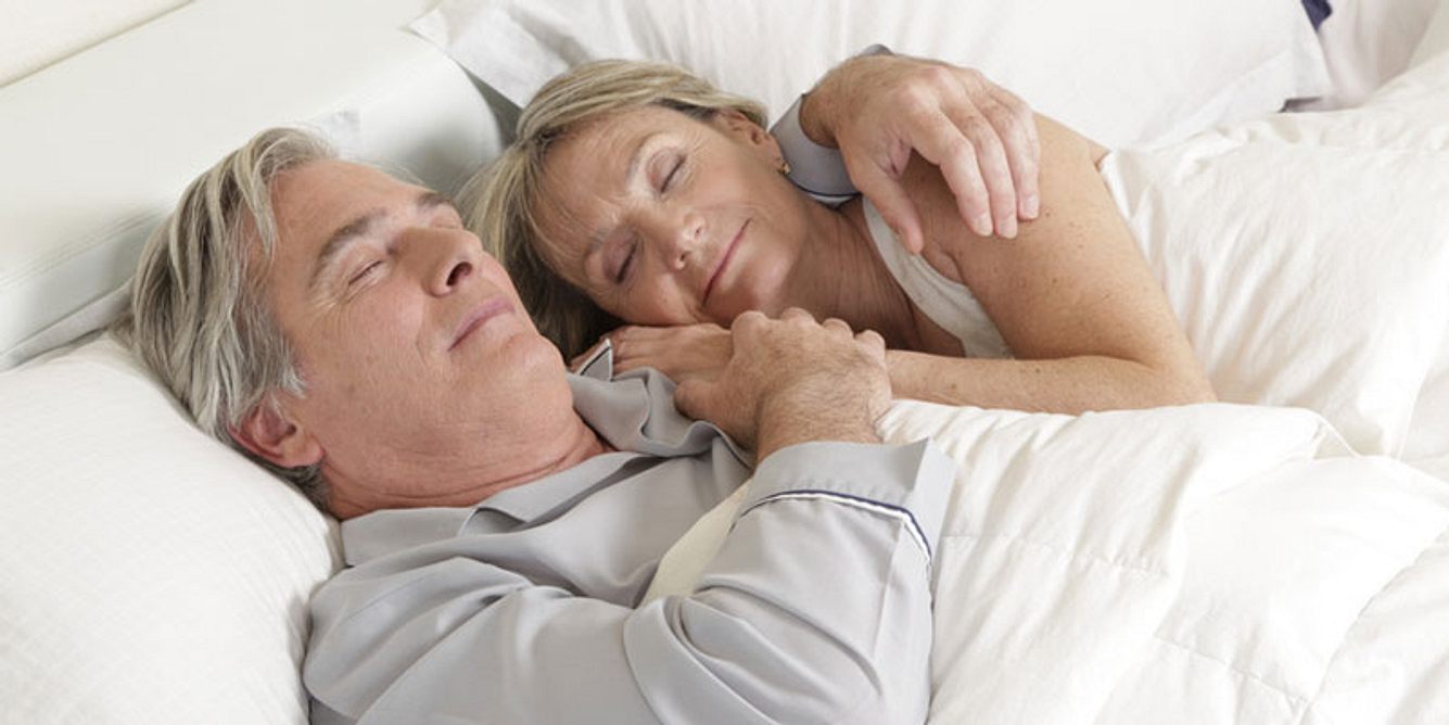 Ein älteres Paar schläft nebeneinander im Bett