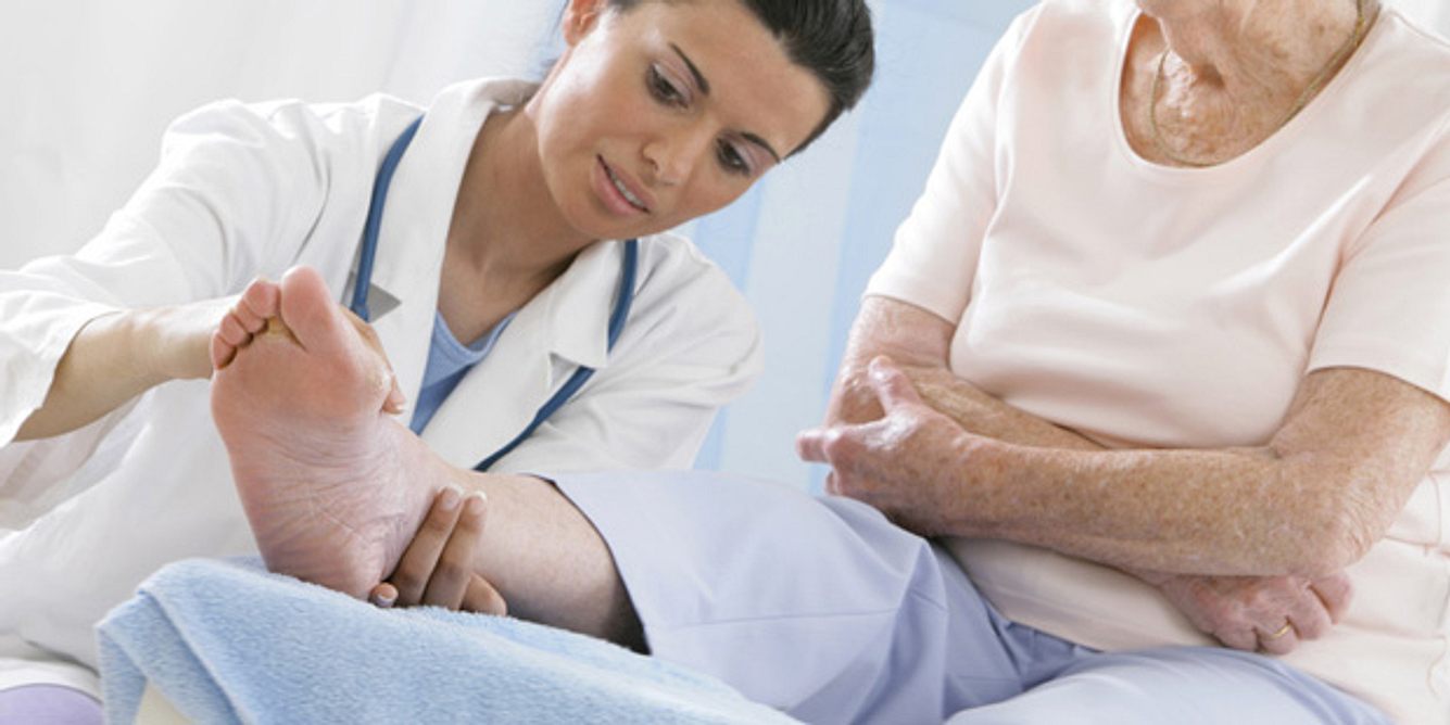 Eine Ärztin untersucht das Bein einer Seniorin