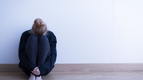 Frau mit Agoraphobie sitzt auf dem Boden - Foto: iStock/KatarzynaBialasiewicz