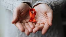 Person hält rote AIDS-Schleife. - Foto: iStock / burakkarademir