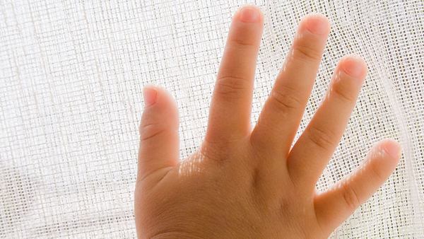 Babyhand hinter einem Vorhang - Foto: Alamy