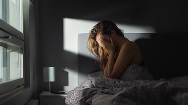 Frau sitzt nachts im Bett und hält sich die Hände vor das Gesicht - Foto: iStock/Tero Vesalainen