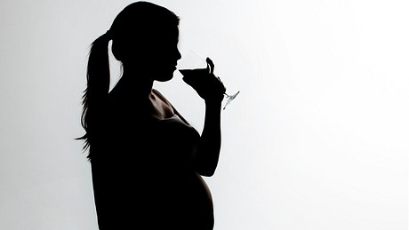 Eine schwangere Frau trinkt aus einem Weinglas - Foto: istock_juankphoto