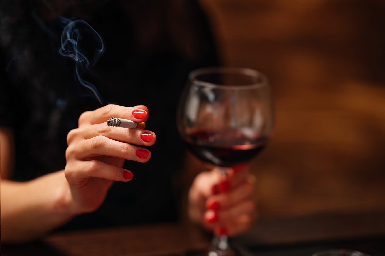 Alkohol und Rauchen Frau trinkt Wein und raucht eine Zigarette