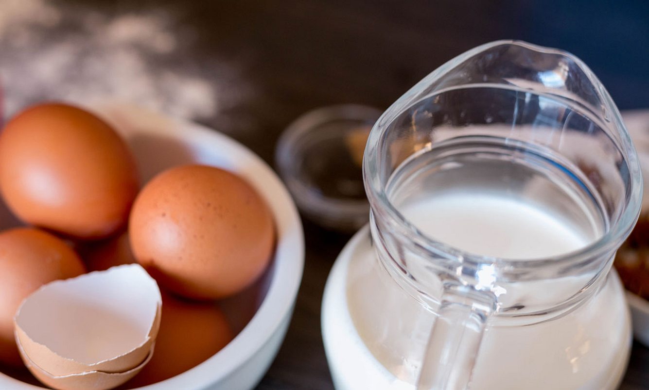 Eier in Schüssel und Milch in Kanne