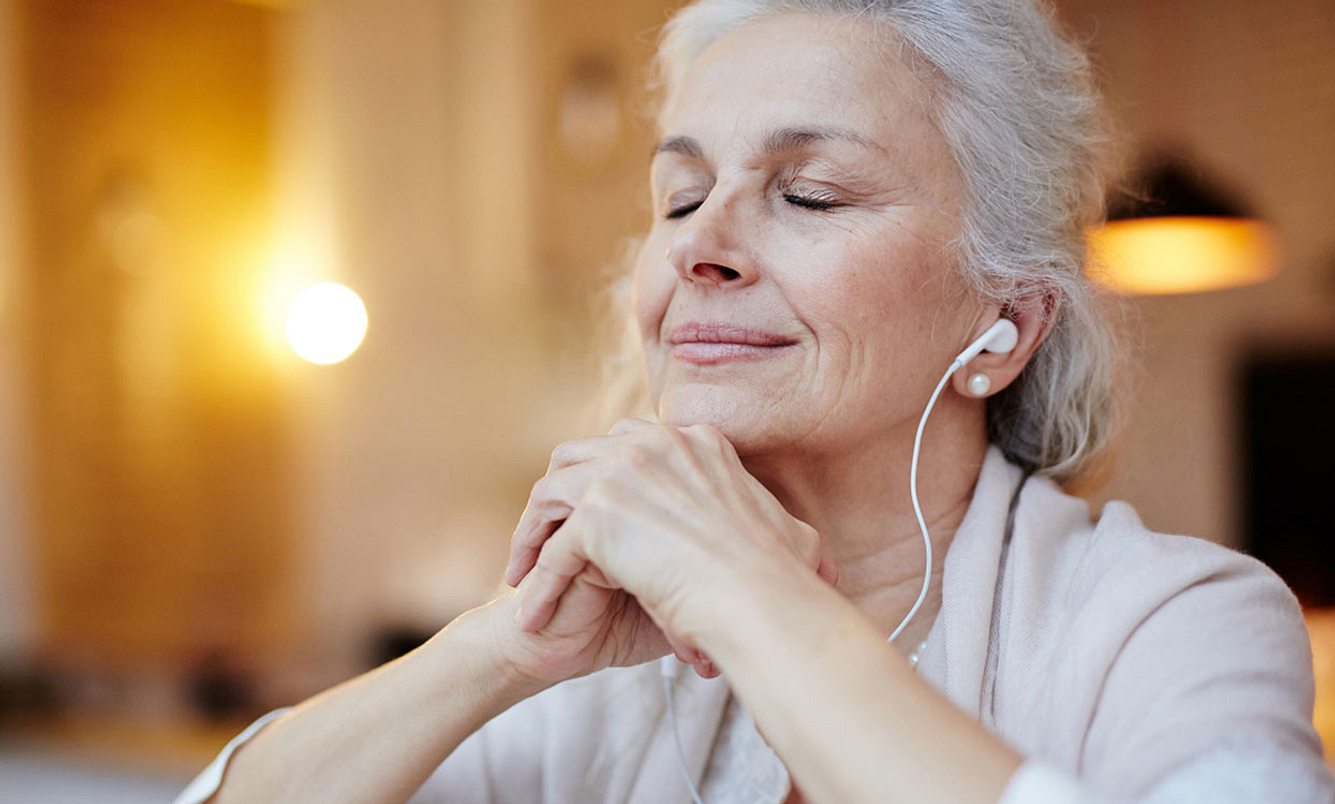 Ältere Frau hört mit Kopfhörern Musik