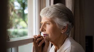 Eine alte Frau schaut aus dem Fenster - Foto: iStock_Ridofranz