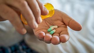 Person schüttet Pillen aus Dose auf Hand - Foto: iStock/ Ridofranz