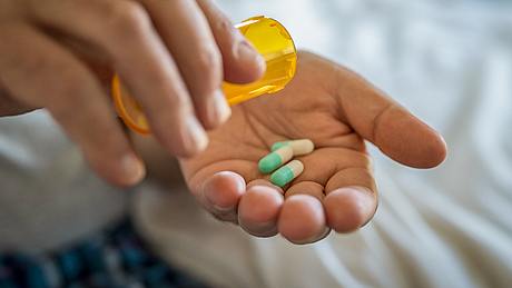 Person schüttet Pillen aus Dose auf Hand - Foto: iStock/ Ridofranz