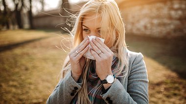 blonde Frau mit Taschentuch draußen - Foto: iStock/bojanstory