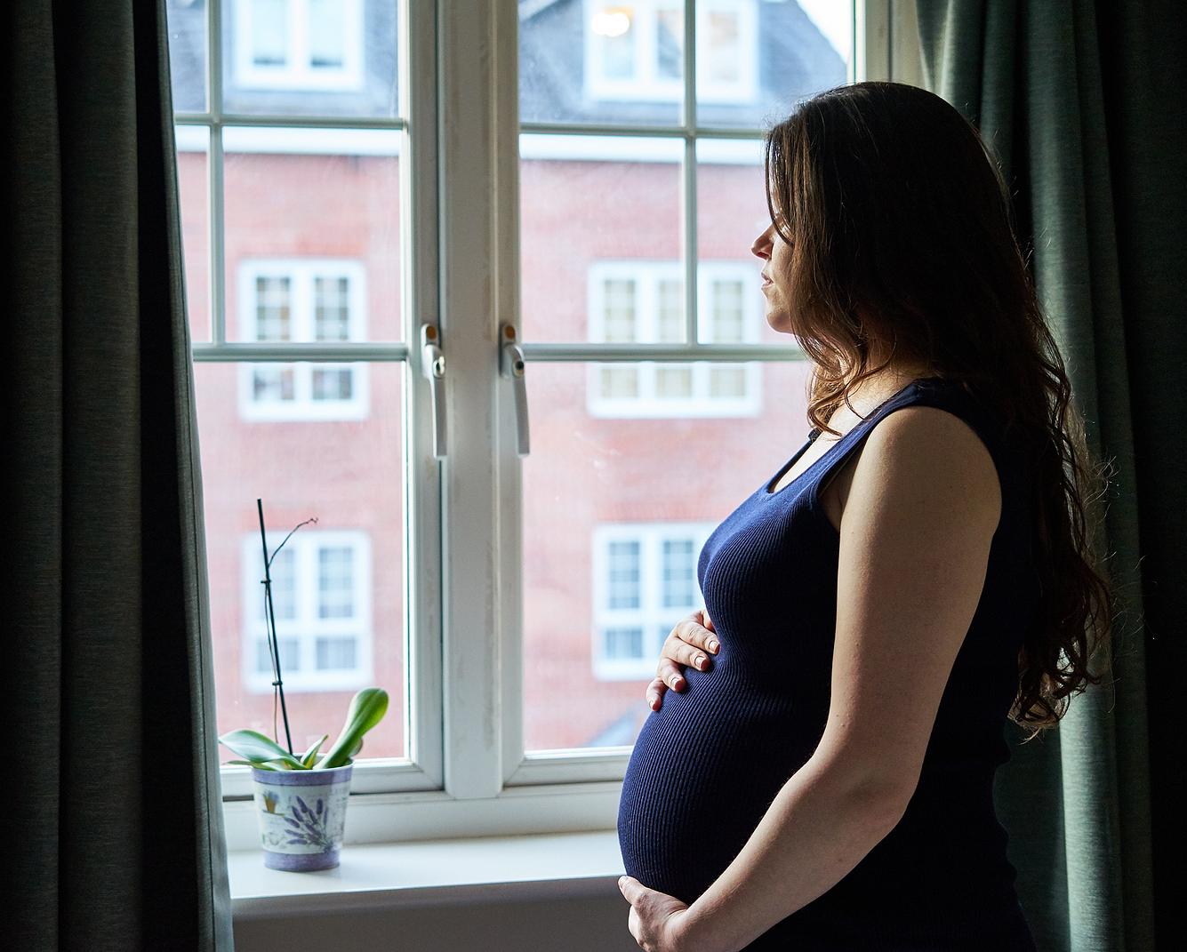 angst-vor-geburt Schwangere Frau schaut aus dem Fenster.