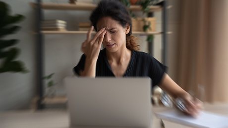 Frau sitzt am Laptop und hat Angstschwindel - Foto: iStock/fizkes