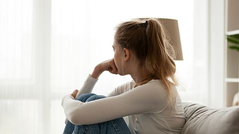 Eine Frau sitzt angespannt auf dem Sofa - Foto: iStock_fizkes