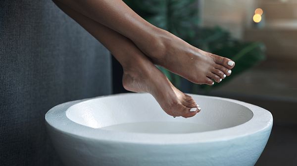 Nackte Füße einer Frau über einer weißen Schüssel - Foto: iStock / PeopleImages