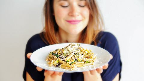 Junge Frau hält einen Teller mit Pasta vor sich und lächelt mit geschlossenen Augen - Foto: iStock/wernerimages