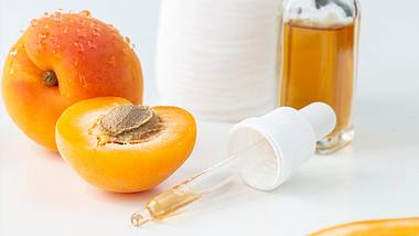 Aprikosenkernöl mit Pipette und einer Aprikose liegen auf weißem Untergrund - Foto: iStock/solidcolours