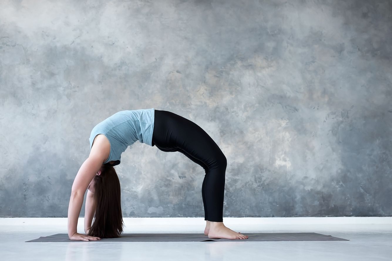 Frau praktiziert die Yoga-Haltung aufwärts gerichteter Bogen