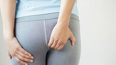 Frau fässt sich an Po - Foto: iStock/Rattankun Thongbun