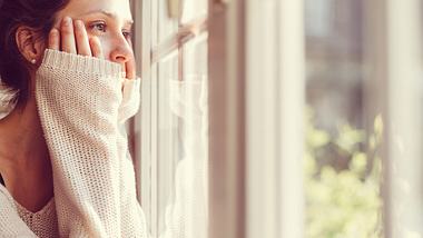 Eine Frau schaut aus dem Fenster - Foto: iStock/martin-dm