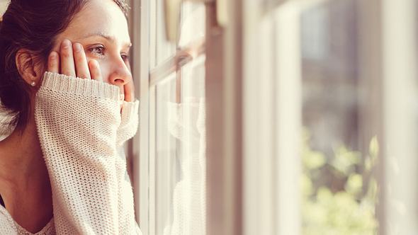 Eine Frau schaut aus dem Fenster - Foto: iStock/martin-dm