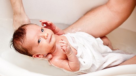 Baby wird in der Badewanne gehalten - Foto: istock/jurasy