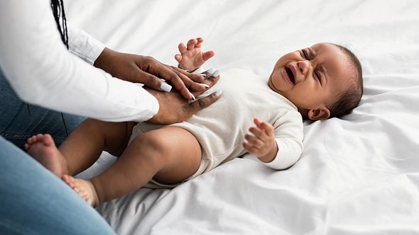 Mutter drückt Baby auf den Bauch - Foto: iStock/Prostock-Studio