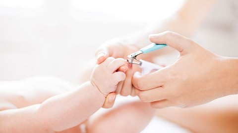Mutter schneidet ihrem Baby die Fingernägel. - Foto: iStock/ Alija