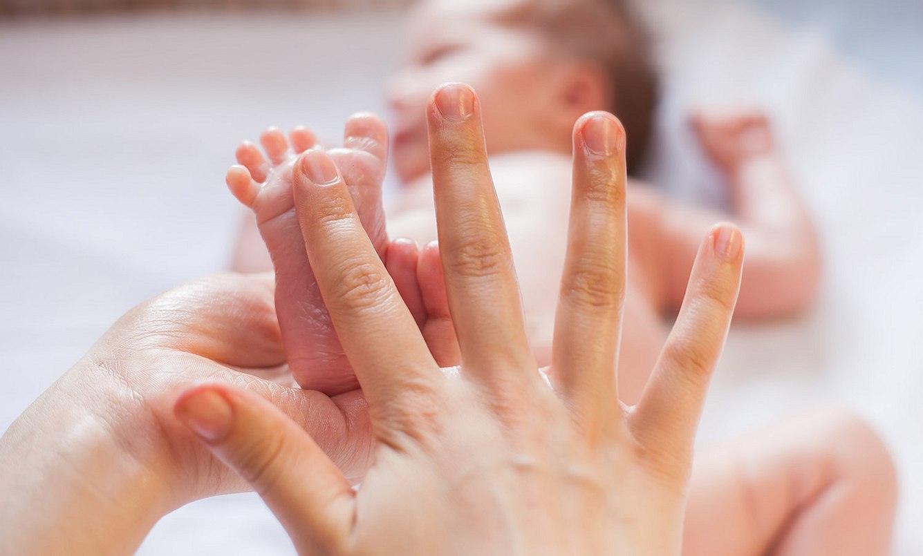 Person massiert Babyfüße
