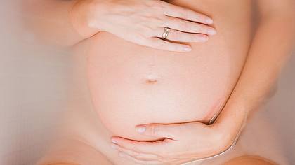 Schwangere liegt in der Badewanne und berührt ihren Bauch - Foto: iStock/Spanishalex