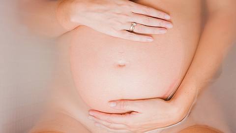Schwangere liegt in der Badewanne und berührt ihren Bauch - Foto: iStock/Spanishalex