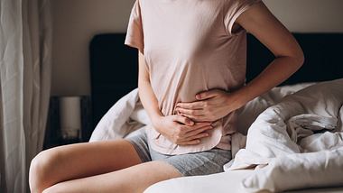 Eine junge Frau hält sich den Bauch - Foto: iStock/Mariia Skovpen