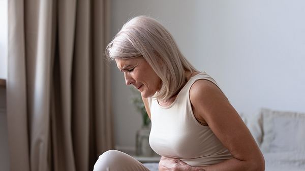 Frau mit Bauchschmerzen in der Mitte hält sich den Bauch - Foto: iStock/fizkes