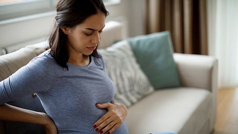 Schwangere Frau hat Bauchschmerzen und hält sich den Bauch - Foto: iStock/damircudic
