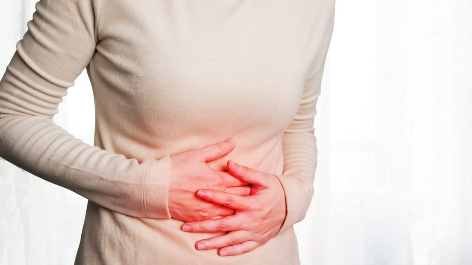 Frau hält sich den Bauch - Foto: iStock/Nitcharee Sukhontapirom