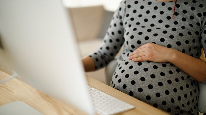 Eine Schwangere sitzt am Computer - Foto: iStock/damircudic