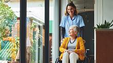 Eine alte Frau in einem Rollstuhl mit einer Betreuerin.  - Foto: iStock/Dean Mitchell