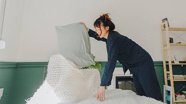 Frau schüttelt das Bett aus - Foto: iStock/AleksandarNakic