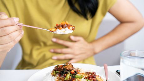 Frau mit Blähungen beim Essen - Foto: iStock/Doucefleur