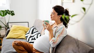 Schwangere Frau mit Tee sitzt auf dem Sofa - Foto: iStock/Nastasic