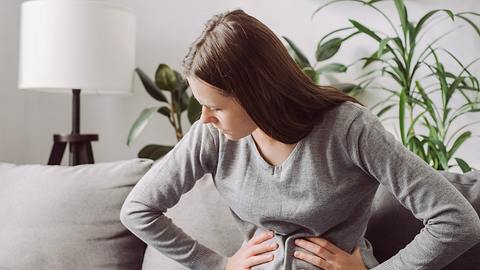 Frau mit Blähungen hält sich den Bauch - Foto: iStock/Yurii Yarema