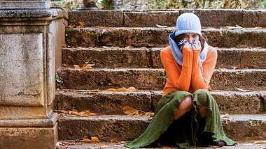 Eine Frau sitzt auf einer Steintreppe - Foto: iStock/JoseASReyes
